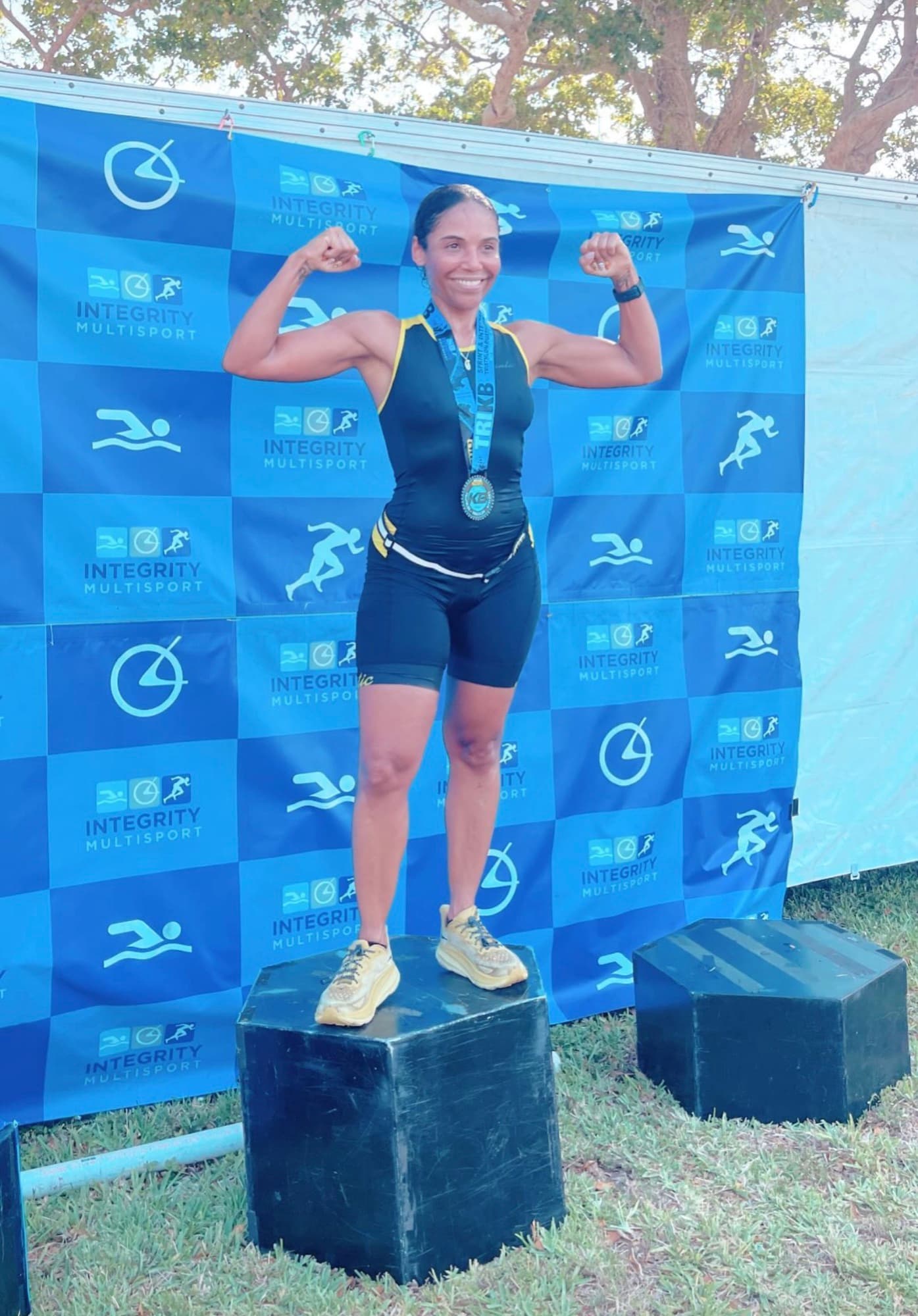 Lisa on a triathlon podium with a finisher medal