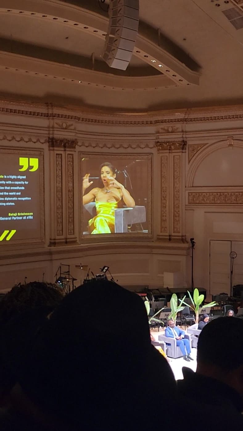 Lisa Francoeur featured on the main screen in a yellow gown at Carnegie Hall