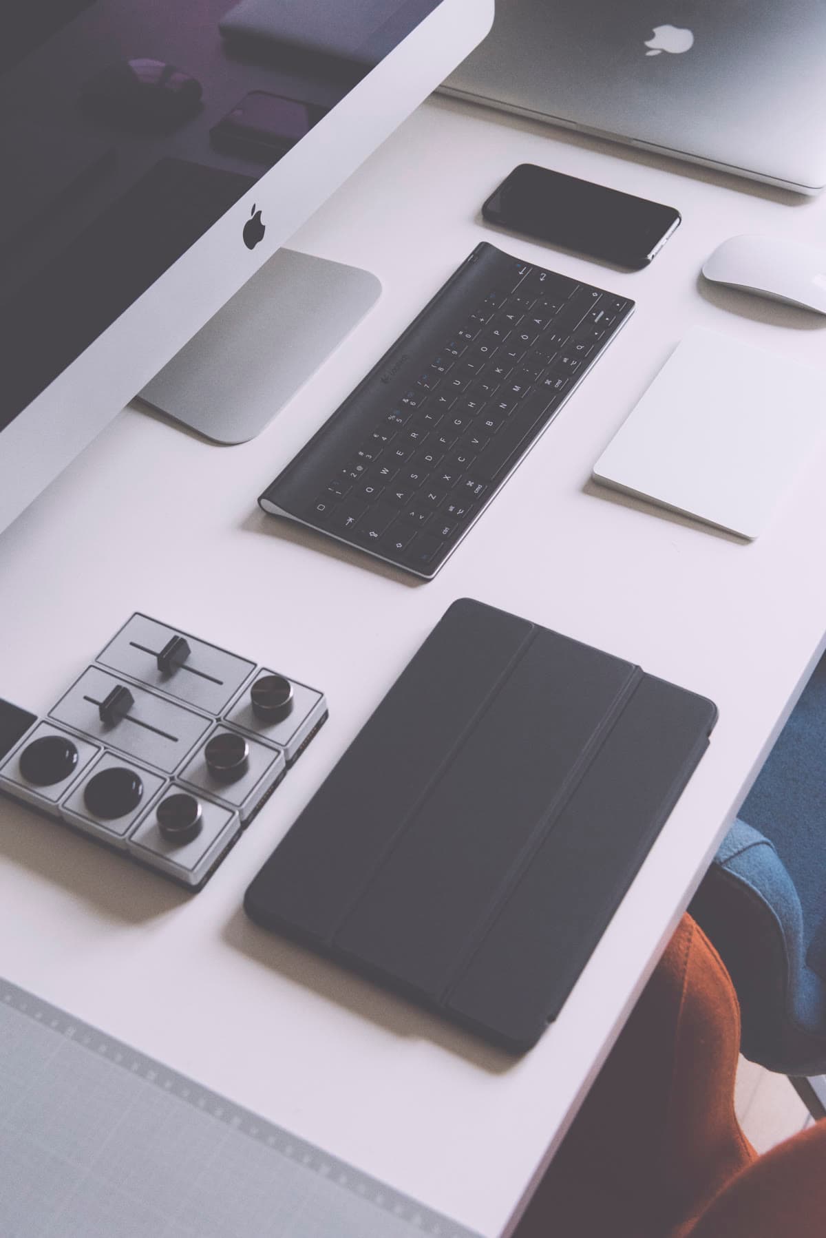 A desk with a MacBook, iPhone, and other Apple devices arranged together